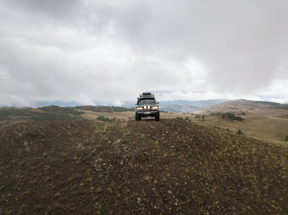Old car parked on hill near mountains in valley · Free Stock Photo