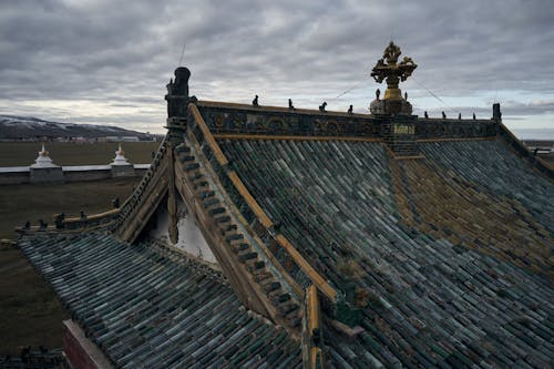 Free From above of ancient Erdene Zuu Buddhist monastery with tiled roof and decorative roof elements under overcast sky in evening Stock Photo