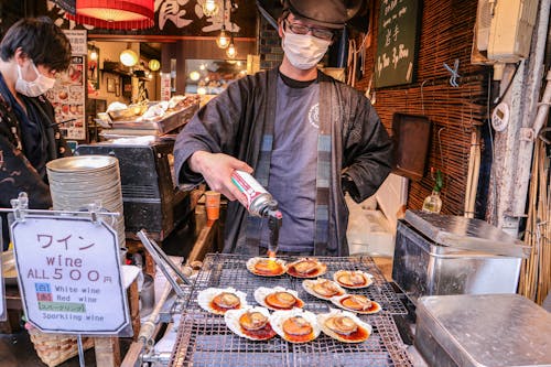 Free Asian man in mask frying clams on street market Stock Photo