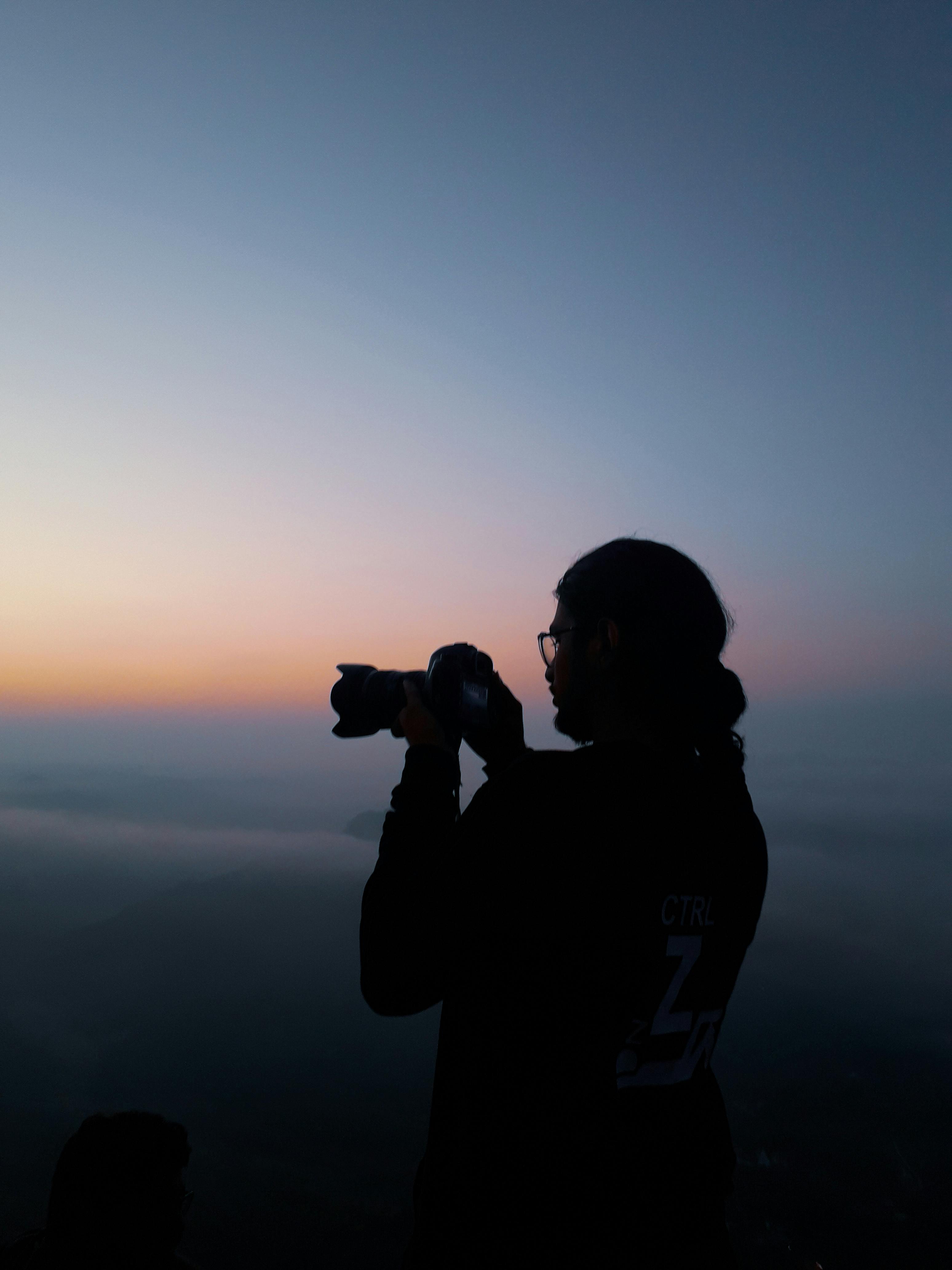 Free Anonymous photographer taking pictures of sunset Stock Photo
