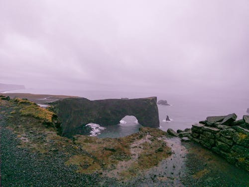 Rough rocky cliff and seawater located against cloudy sky on stormy day in countryside