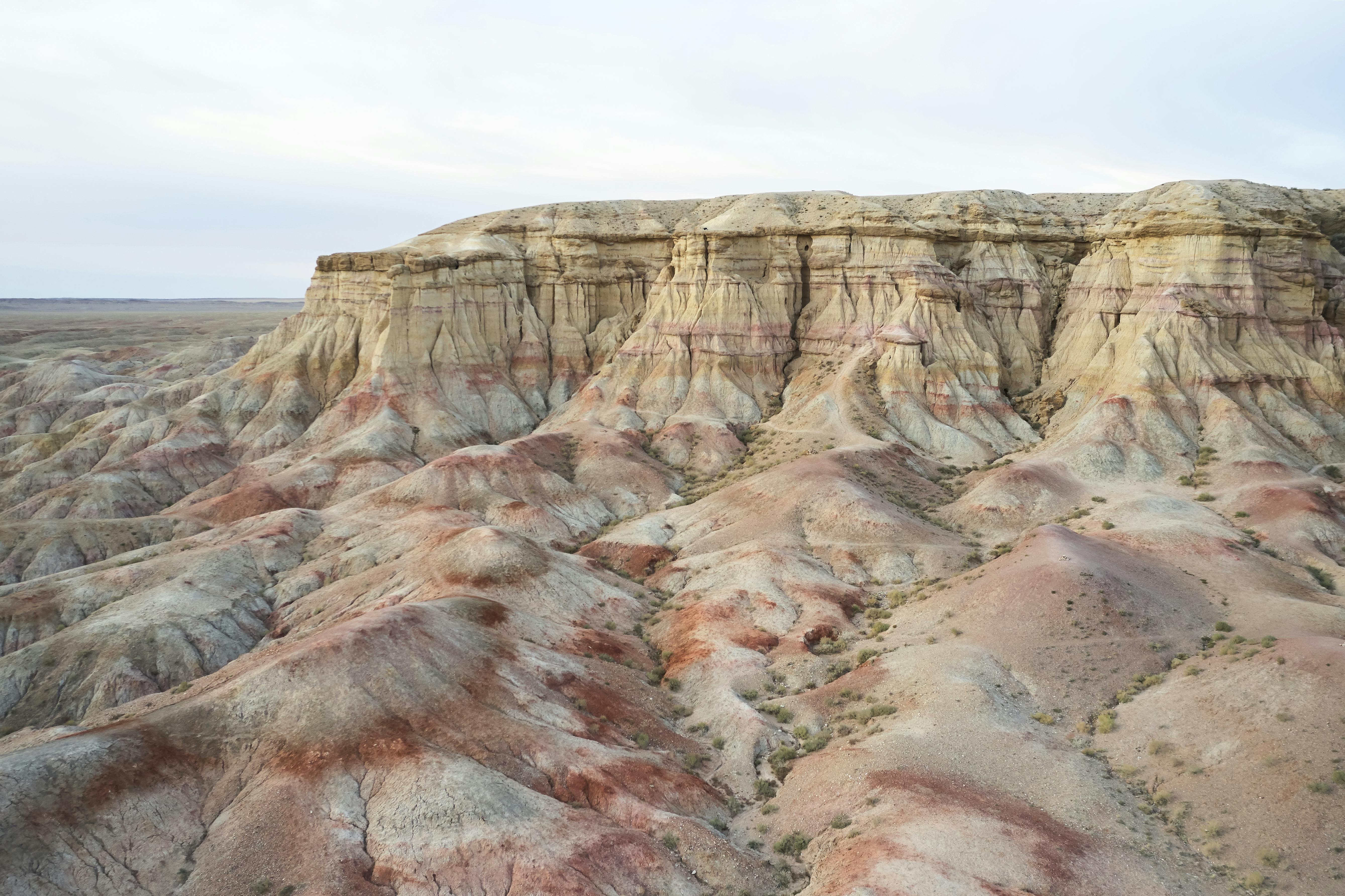 Rough green terrain near rocky mountain · Free Stock Photo