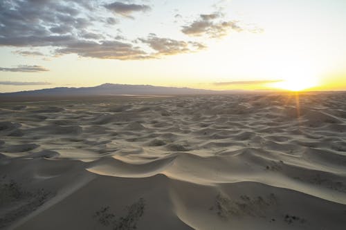 Magnificent sand dunes under cloudy sky at sunset