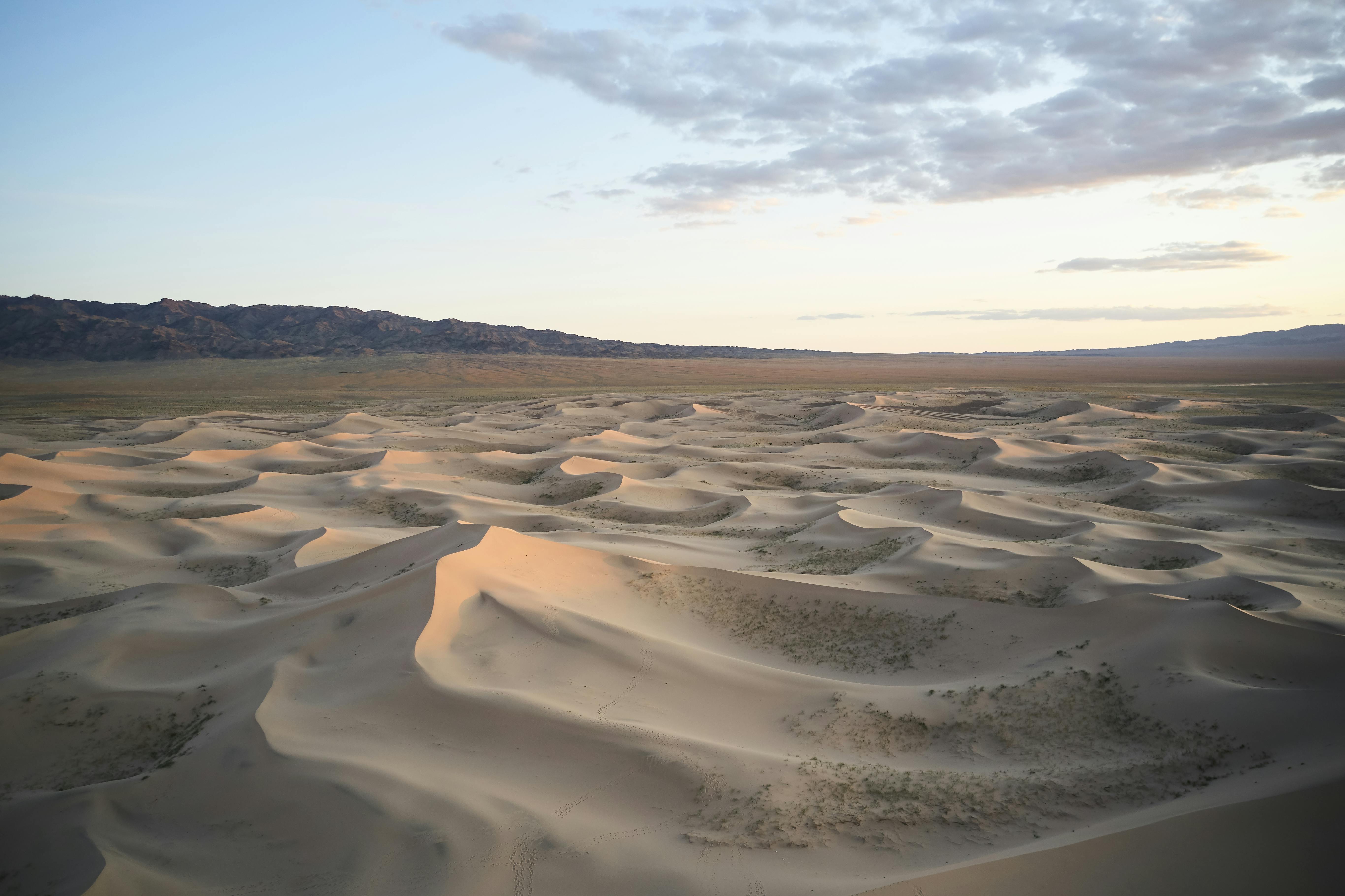 Uneven sand surface in desert under cloudy sky · Free Stock Photo