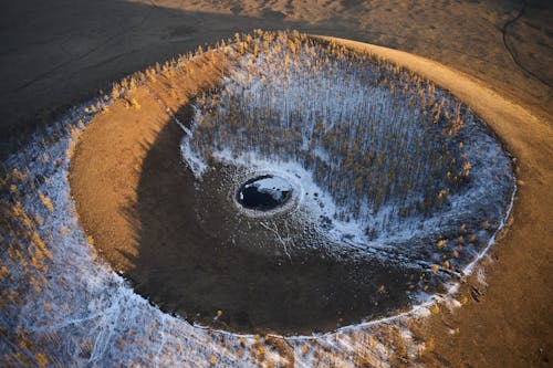 Black puddle in round sand cavity in evening