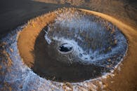 Black puddle in round sand cavity in evening
