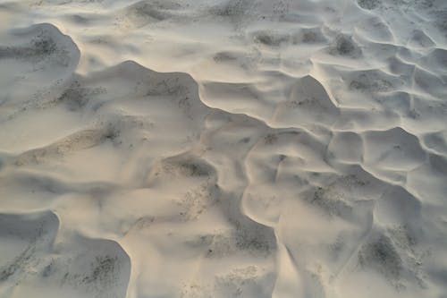 Sandy terrain forming wavy lines and small hills in afternoon
