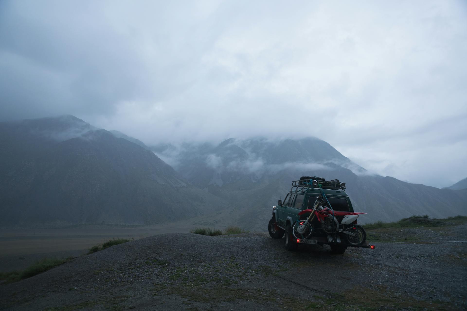 A parked SUV with bicycles at dusk overlooking misty mountains, perfect for adventure travel.