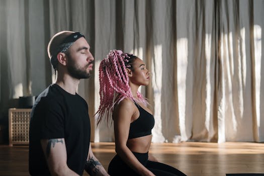 A man and woman meditating in a yoga studio, focusing on relaxation and wellness.