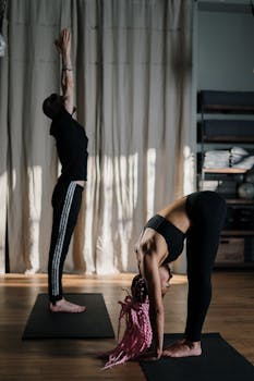 Two individuals practicing yoga in a calm studio, focusing on flexibility and wellbeing.