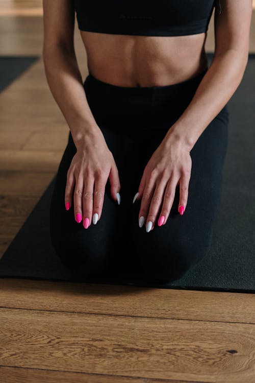 Woman in Black Tank Top and Black Leggings Sitting on Black Yoga Mat