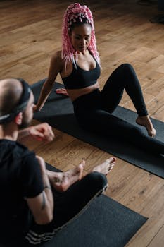 A woman with pink hair practices yoga indoors, promoting health and wellness.