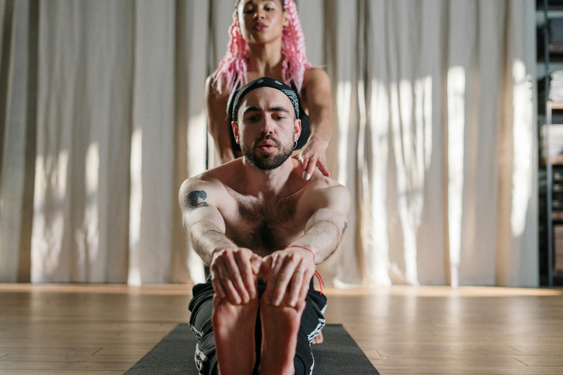 A yoga instructor assisting a student in a studio setting, focusing on health and wellbeing.