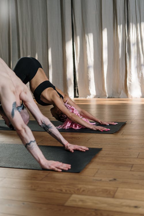 Woman in Black Sports Bra and Black Panty Bending over on Brown Wooden Floor