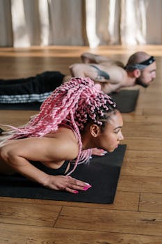 A diverse group of adults practicing yoga on mats indoors, focusing on well-being and fitness.