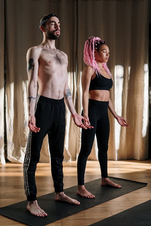 Free Woman in Black Sports Bra and Black Pants Standing Beside Topless Man Stock Photo