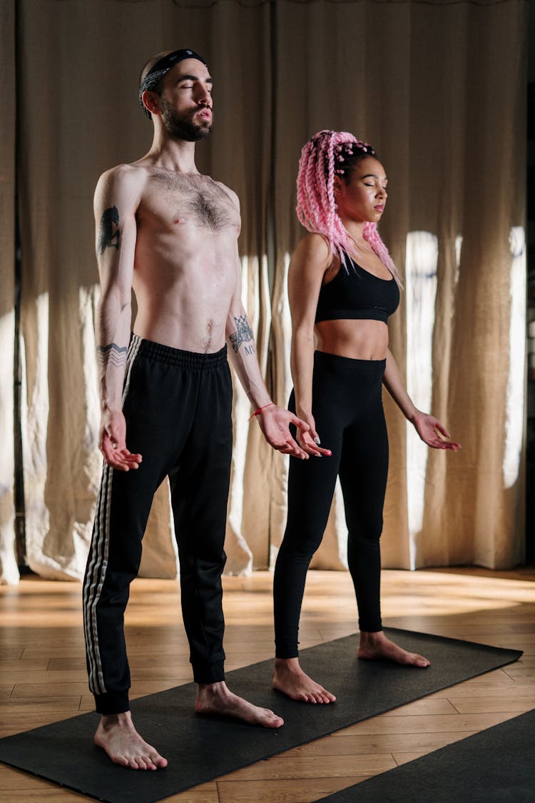 Woman In Black Sports Bra And Black Pants Standing Beside Topless Man