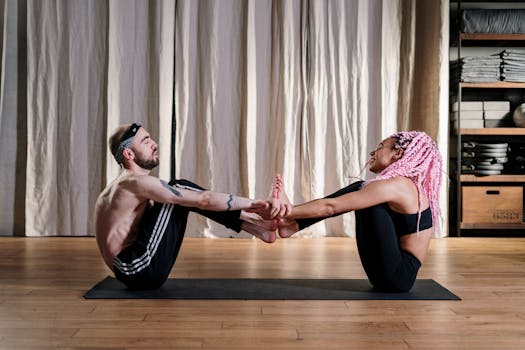 A diverse couple practicing yoga indoors, focusing on flexibility and wellbeing.