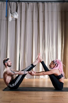 Two individuals practicing partner yoga indoors with a focus on balance and flexibility.