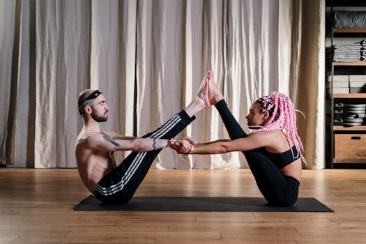 Two individuals performing a partnered yoga pose in a serene studio environment for enhanced fitness.