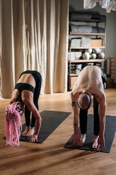 Two yoga practitioners stretching indoors in a cozy studio.