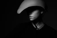 一位模特戴着独特头盔，在阴影中呈现艺术黑白肖像