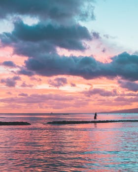 Serene beach landscape at sunset with pastel pink and blue skies reflecting on water.