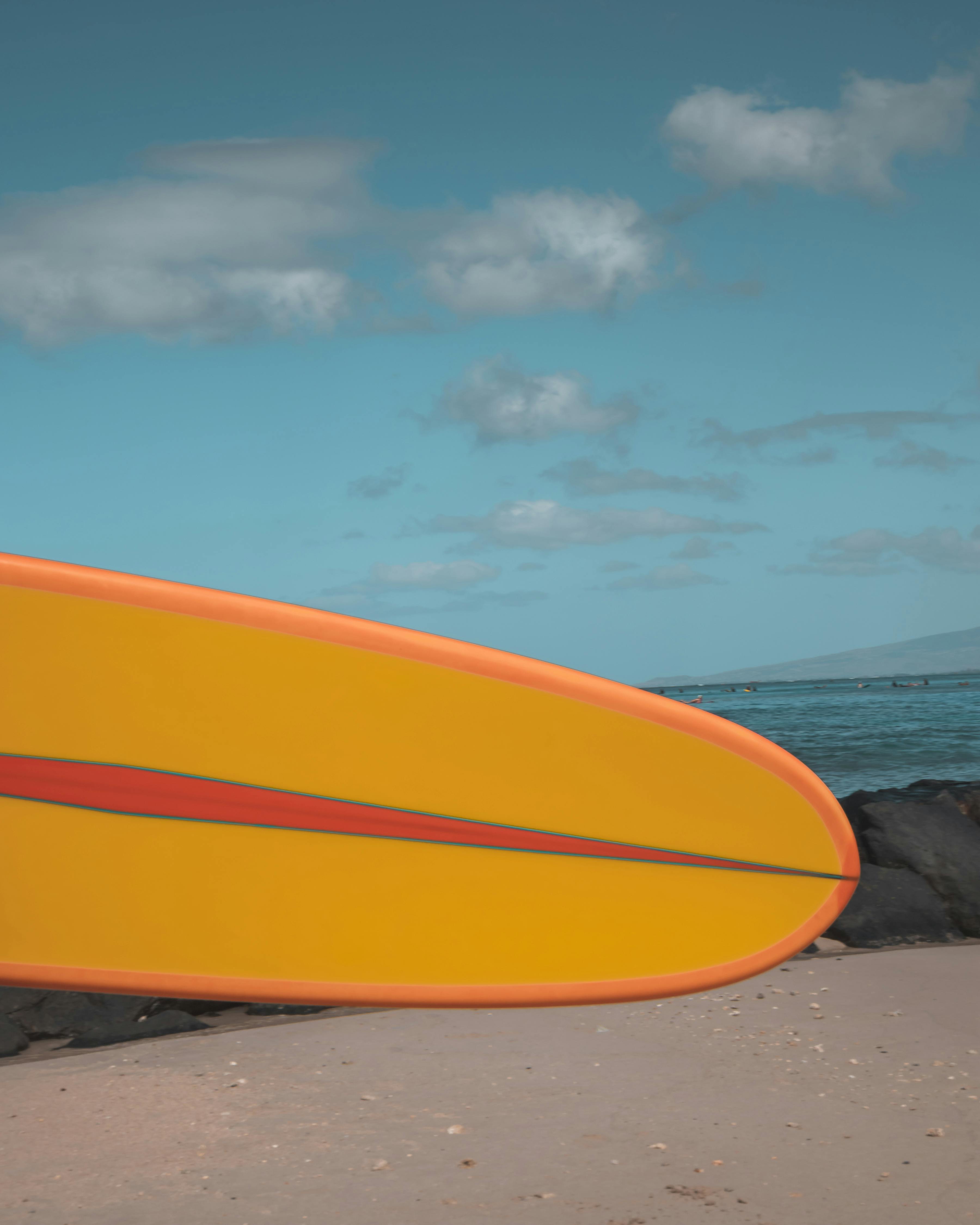 orange surfboard on beach shore