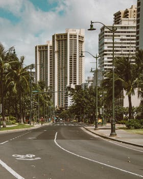 Photo by Jess Loiterton Serene urban street scene with tall buildings and palm trees in Waikiki, Hawaii.