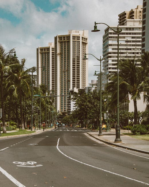 Photo by Jess Loiterton Serene urban street scene with tall buildings and palm trees in Waikiki, Hawaii.