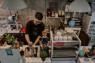 From above of serious bearded ethnic male barista in casual wear and eyeglasses working in cafeteria
