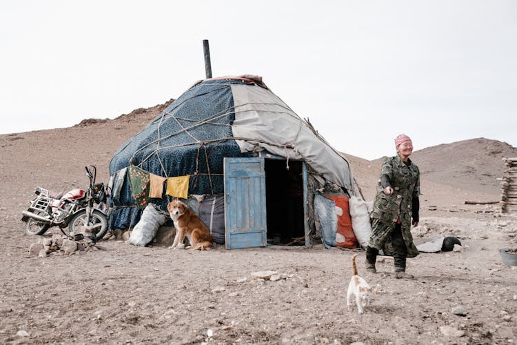 Senior Mongolian Woman Pointing At Cat Walking Near Home Ger