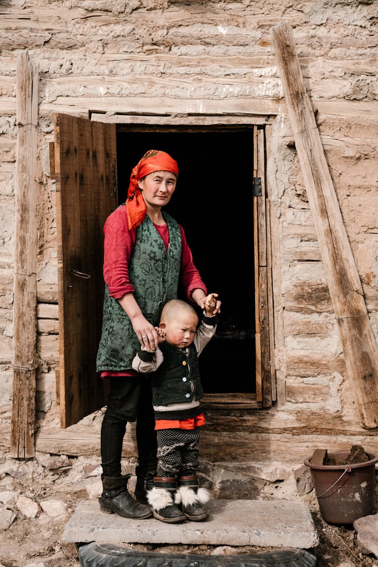 Local Ethnic Woman Standing Outside House With Child