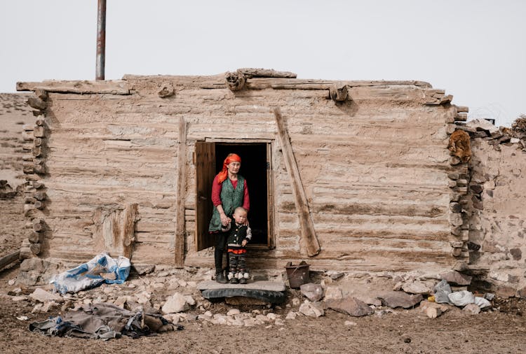 Ethnic Woman And Little Boy Standing Near Destroyed House