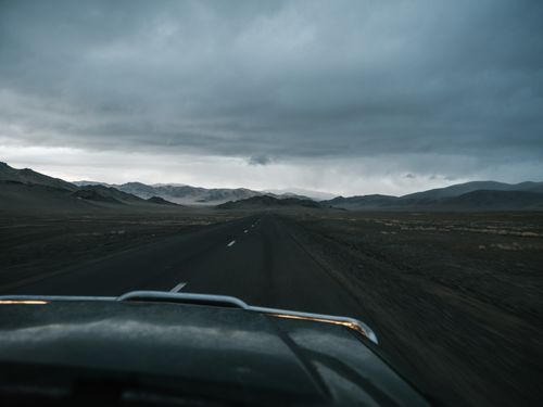 Free Asphalt road running away to remote mountains in haze and prairie seen from car in cloudy day Stock Photo