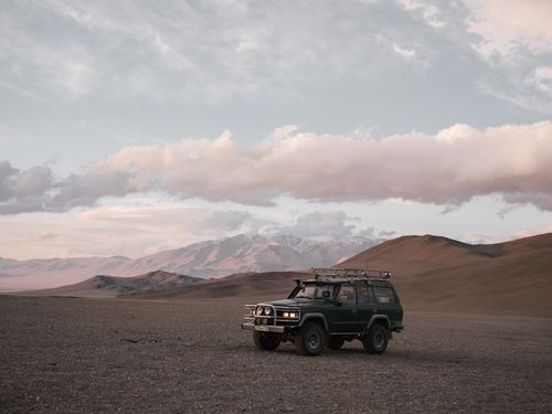 Free Magnificent view of auto with headlamps on parked on sand terrain near ridge under sky with low clouds in evening Stock Photo