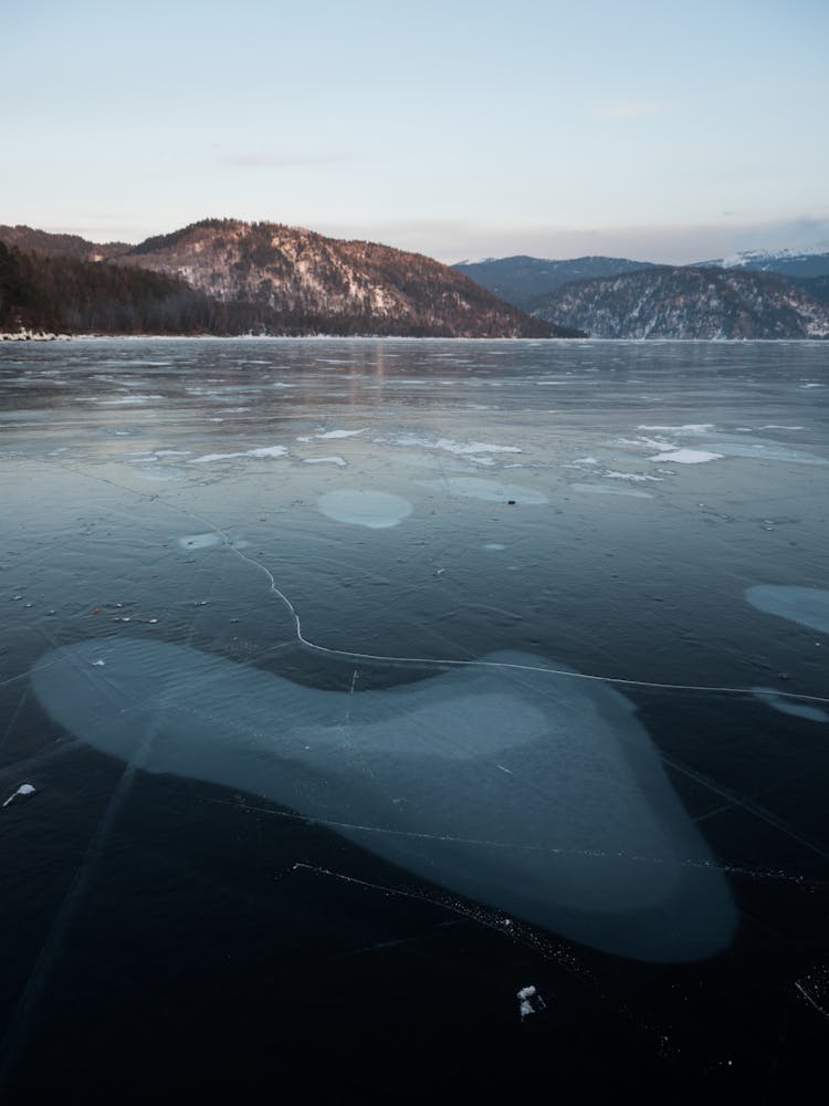 Frozen River Near Ridge Under Blue Sky