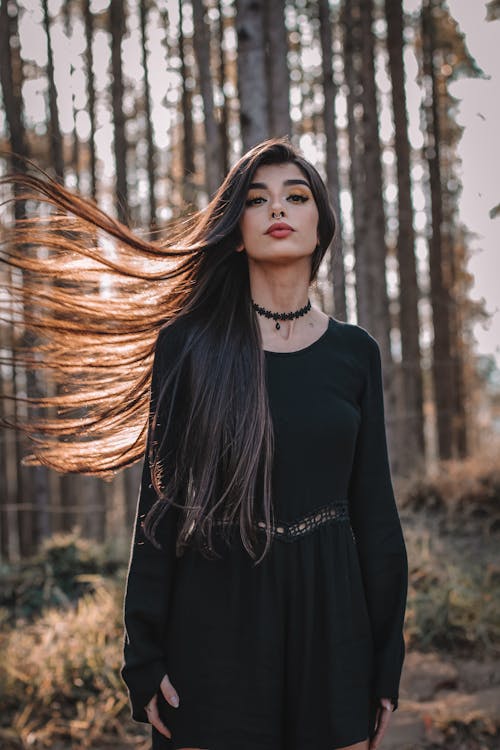 Gorgeous woman with flying hair standing in forest