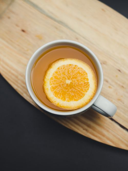 Free A close-up of an orange slice in a mug on a wooden cutting board, perfect for fresh drink inspiration. Stock Photo