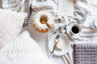 White Ceramic Cup on White Ceramic Saucer Beside Stainless Steel Fork on White Textile