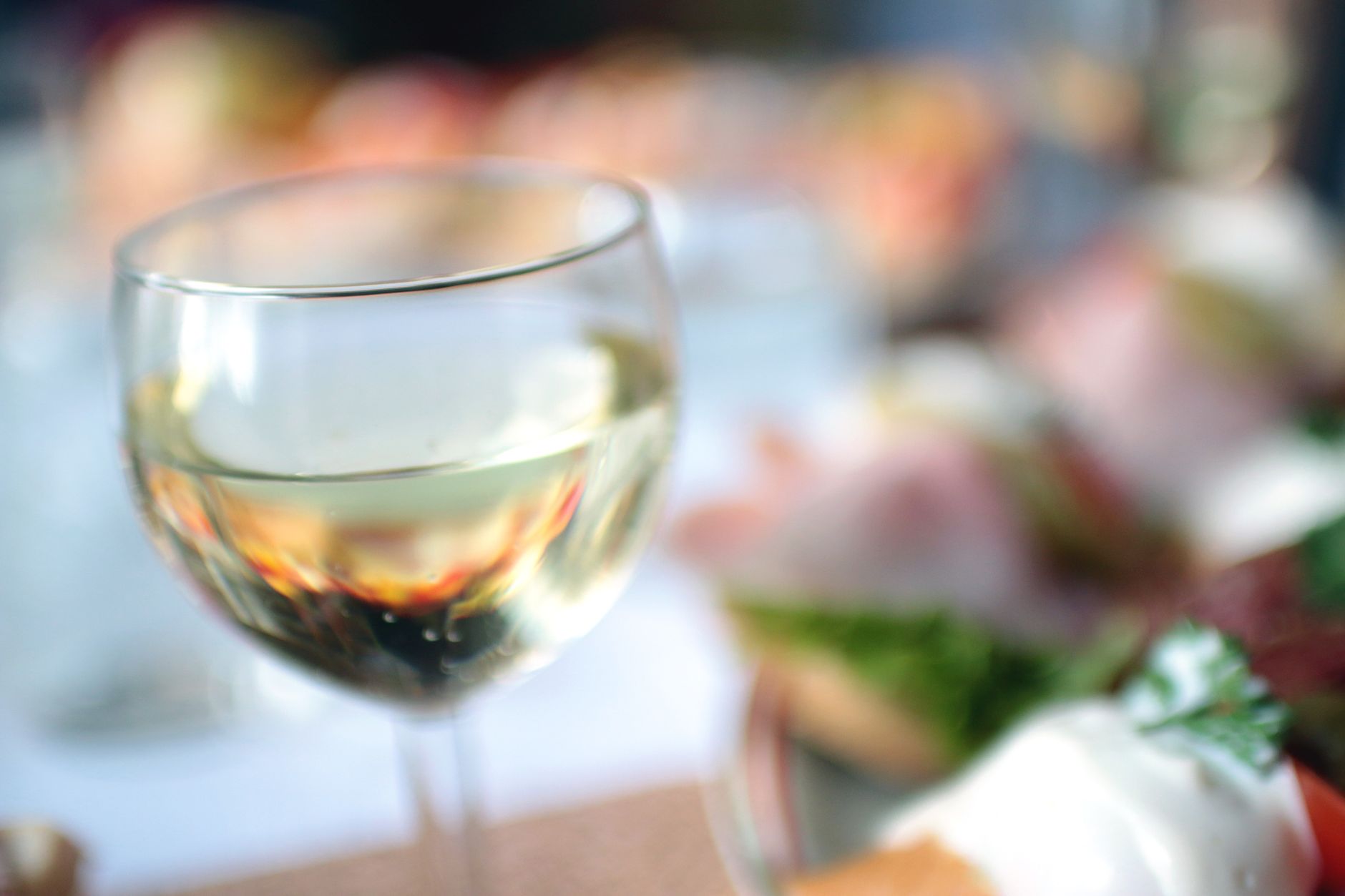 Close-up of natural wine being poured into a glass at a candlelit table with soft bokeh background.