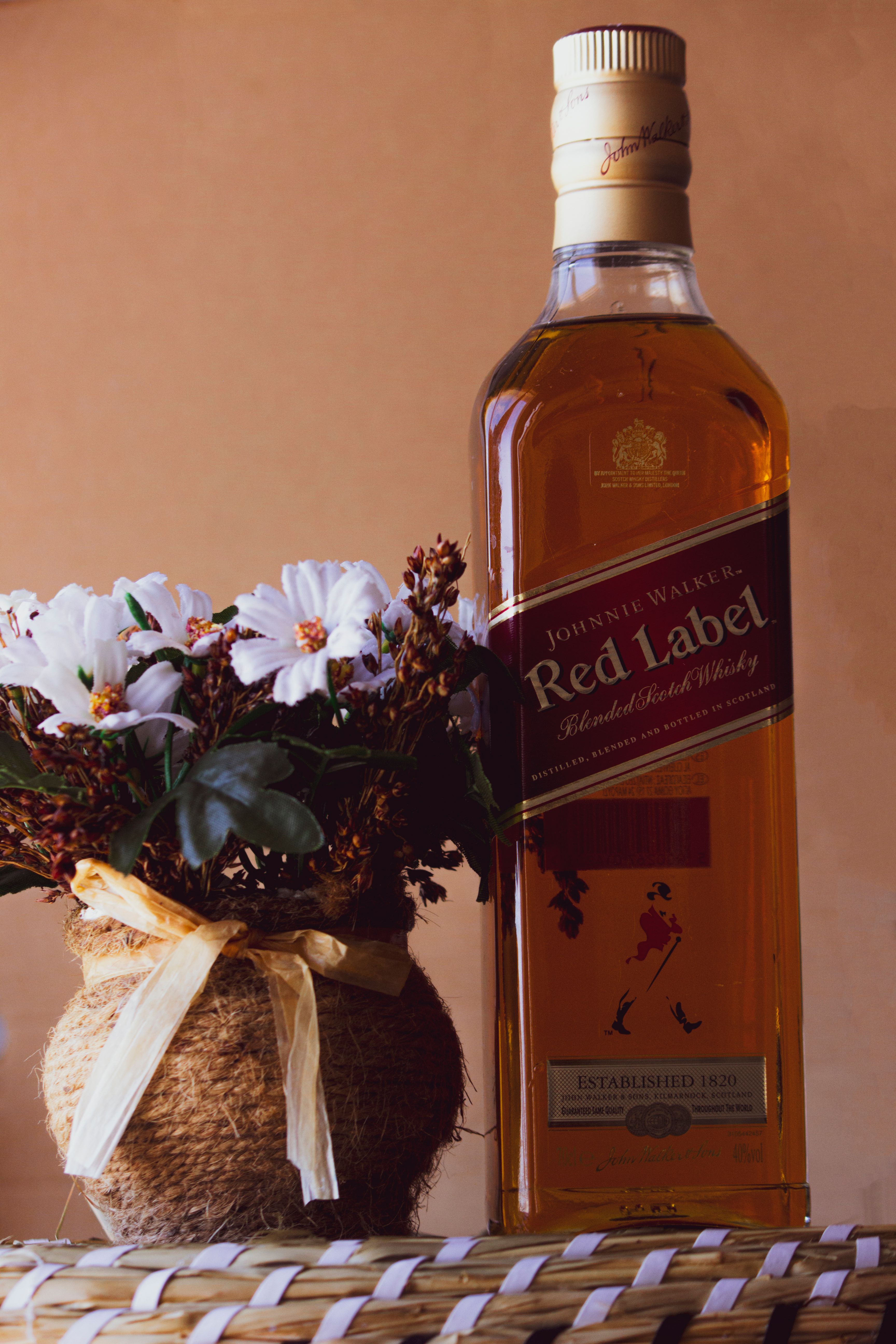 Close-up of a whisky bottle paired with a floral arrangement, ideal for lifestyle promotions.