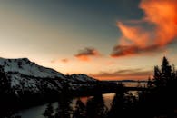 山脉和湖泊上空的日落令人惊叹，天空中飘着雪，色彩鲜艳