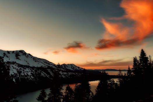 山脉和湖泊上空的日落令人惊叹，天空中飘着雪，色彩鲜艳
