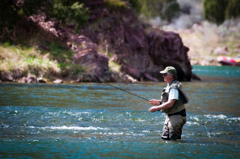 Man fly fishing in a tranquil river surrounded by nature and beautiful scenery
