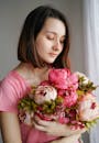 一位年轻女子手持一束美丽的粉色牡丹，散发着优雅与女人味