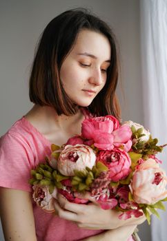 一位年轻女子手持一束美丽的粉色牡丹，散发着优雅与女人味