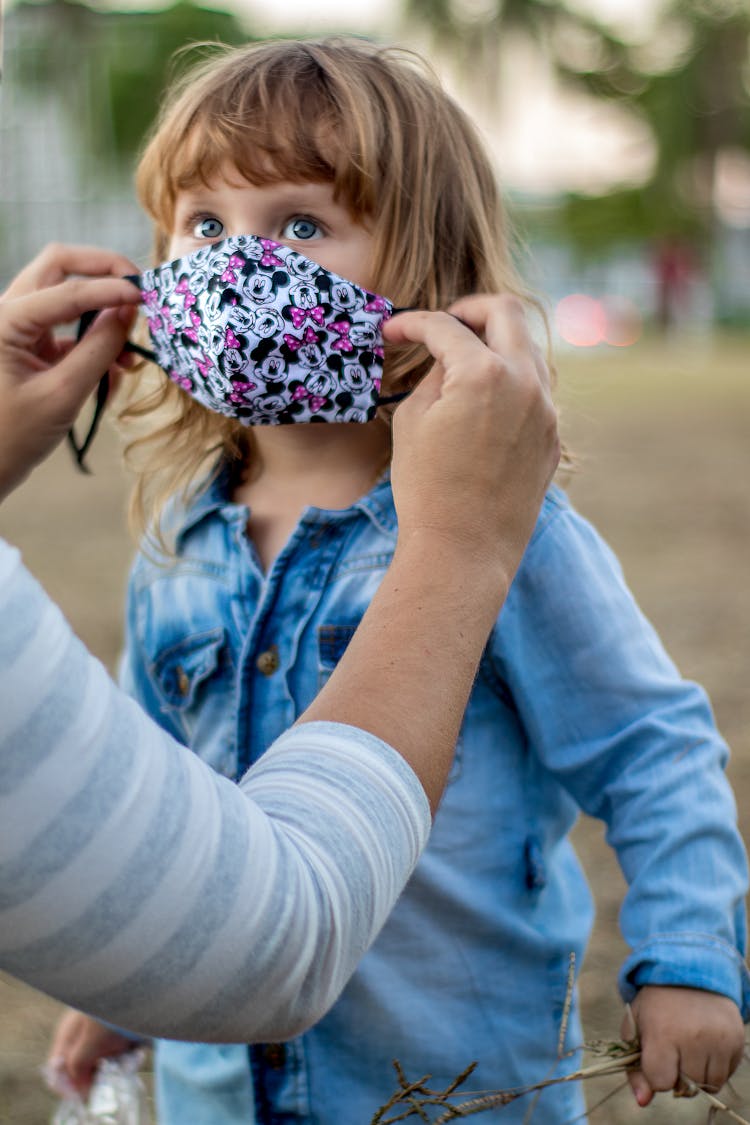 Mother Putting Facial Mask On Little Daughter In Park