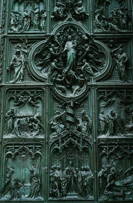 Magnificent details of green bronze door of medieval cathedral church with carved bas reliefs with biblical motives