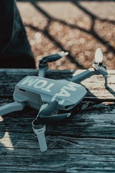 High angle contemporary drone helicopter with four rotors placed on shabby wooden bench in sunny park